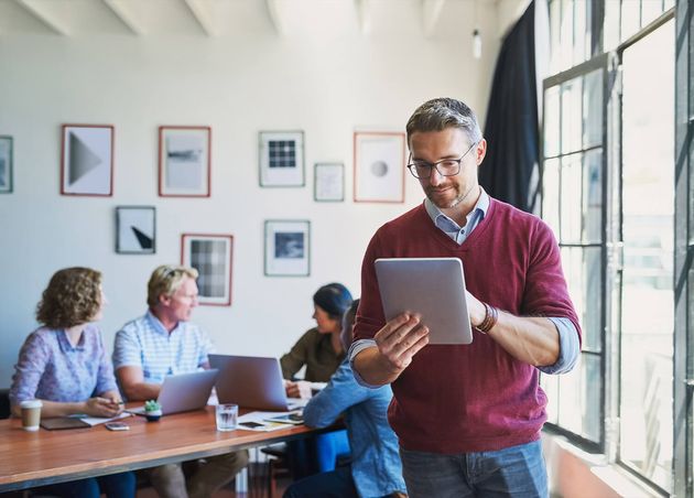 Digital Manager Gets Things Done Shot Mature Man Using Digital Tablet with His Team Background Modern Office