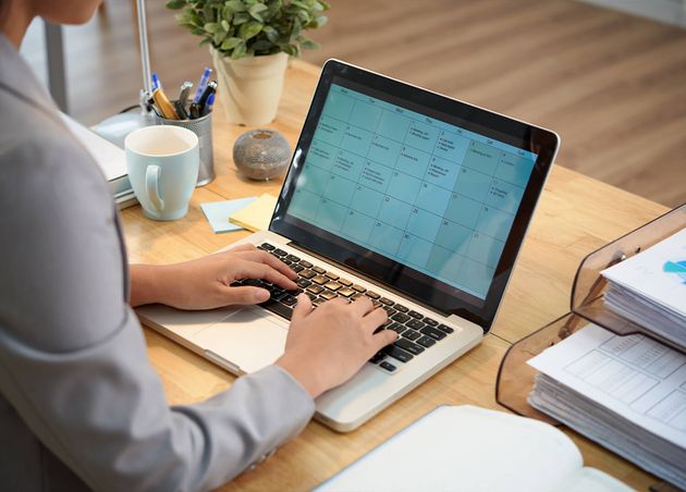 Unrecognizable Businesswoman Sitting Desk with Laptop Looking Calendar