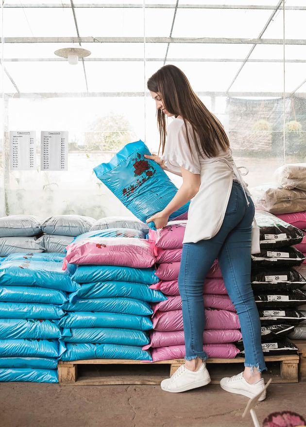 Side View Smiling Young Woman Stacking Plastic Sacks Greenhouse