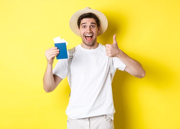 Tourism Vacation Satisfied Male Tourist Showing Passport with Tickets Thumb up Recommending Travel Company Standing Yellow Background