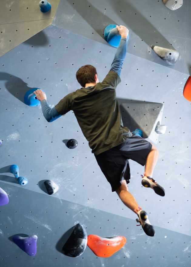 Back View Young Guy Exercising Climbing Gym Caucasian Athlete Sportswear Doing Bouldering Holding Artificial Rocks Wall with Strong Hands Hanging Air Extreme Sport Healthy Lif