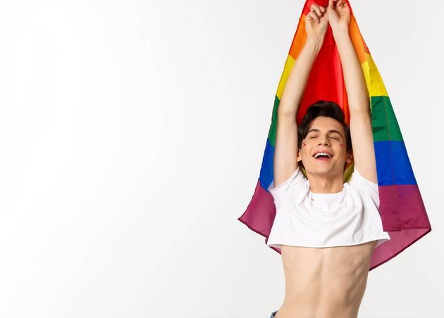 Vertical View Proud Happy Gay Man Raising Lgbtq Rainbow Flag Smiling with Relieved Emotion We