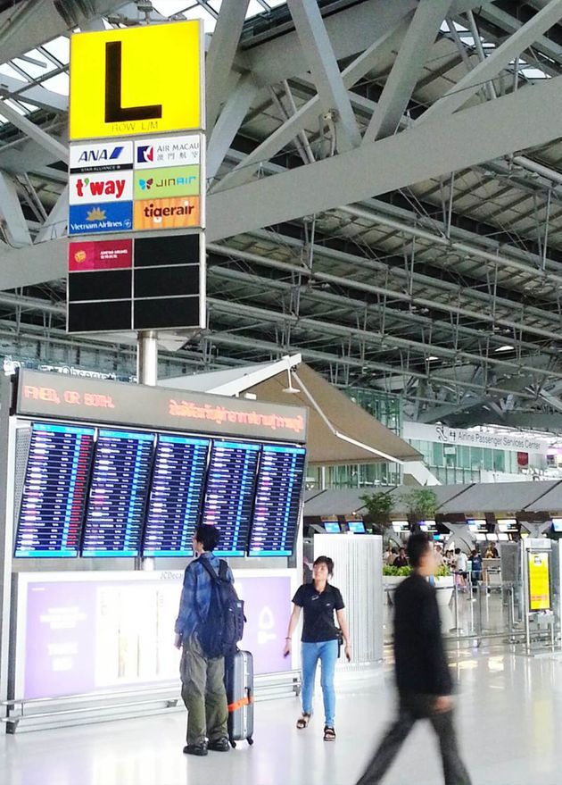 Menschen sehen sich Abflug- und Ankunftsanzeigetafel am Flughafen Suvarnabhumi an