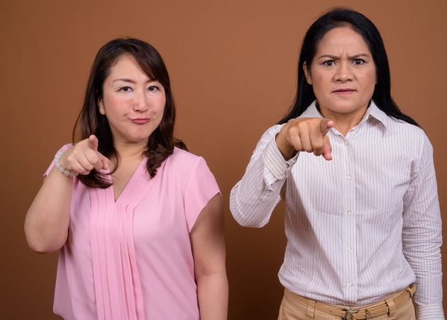 Two Mature Asian Businesswomen Together against Brown Wall