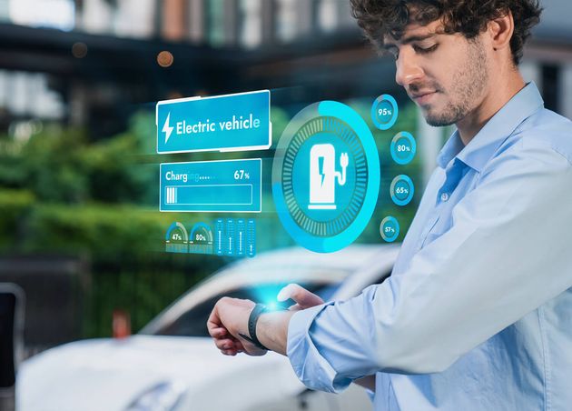 Geschäftsmann überprüft den Ev-Autobatteriestatus Hologramm von Smartwactch beim Aufladen an der Ladestation Moderner städtischer Lebensstil umweltfreundliche Elektroautonutzung Reduzieren Sie Co2