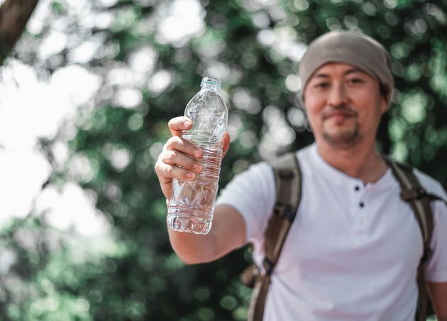 Portrait Asian Traveler Man with Backpack Showing Water Bottle Woodland with Copy Space Vacation Holiday Hobby Concept