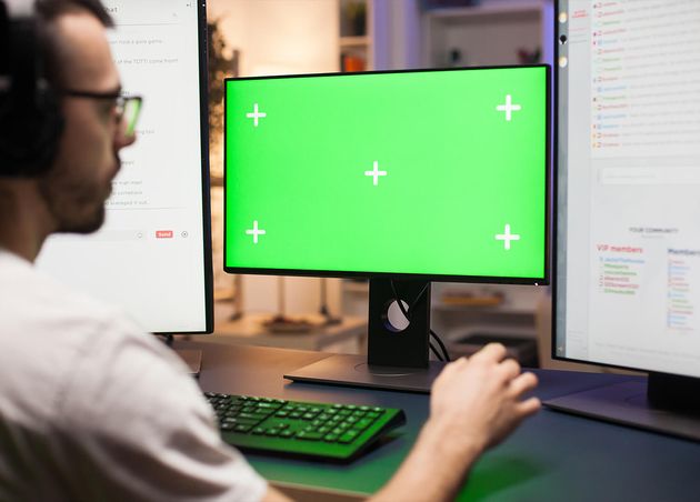 Junger Mann mit Brille spielt Spiele Computer mit grüner Platzierung während des Streamings