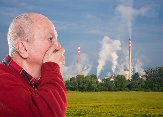 Ecological Concept Senior Man with Face Closed by Hands against Background Pipes Polluting Atmosphere