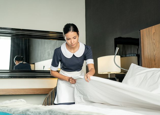 Young Pretty Brunette Maid Putting White Clean Blanket while Changing Bed One Hotel Rooms during Preparation New Guests