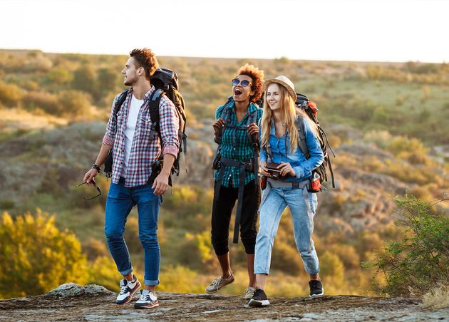 Young Cheerful Travelers with Backpacks Smiling Walking Canyon