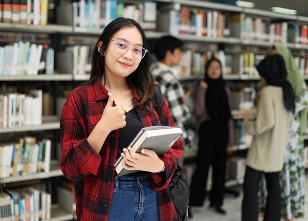 Asian Student Standing Confidently Giving Thumb up while Smiling Hold Book Library