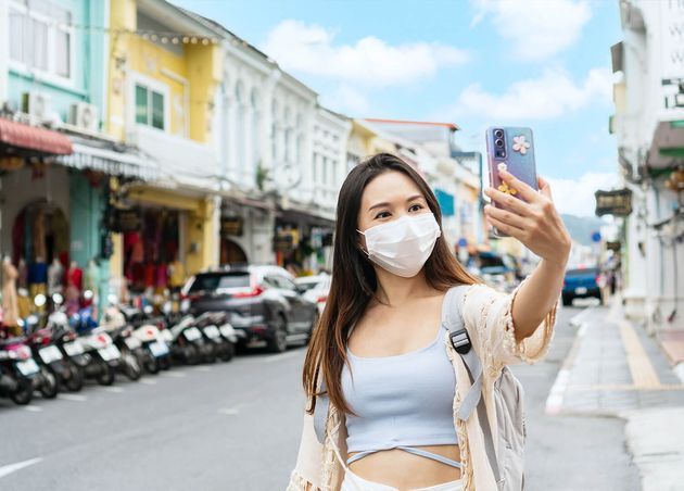 Asian Traveler Wearing Medical Mask Take Photo Video Call with Her Family Smiles while Walking Old Town Phuket Thailand Travel during Covid19 Pandemic New Normal Lifestyle Concept