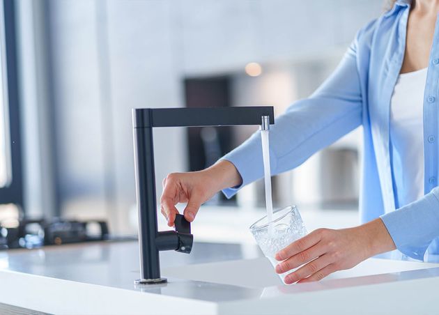 Female Pours Fresh Filtered Purified Water from Tap into Glass Kitchen Home