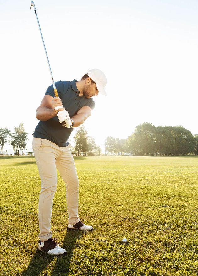 Young Male Golfer Hitting Ball with Club