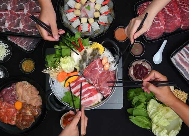 Top View People Eating Shabu Shabu Hot Pot with Fresh Sliced Meat Sea Food Vegetables with Black Background