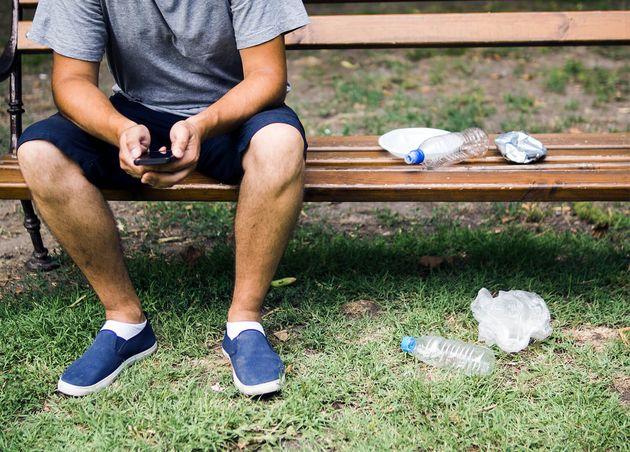 Man Using Cellphone Sitting Bench near Plastic Trash Park
