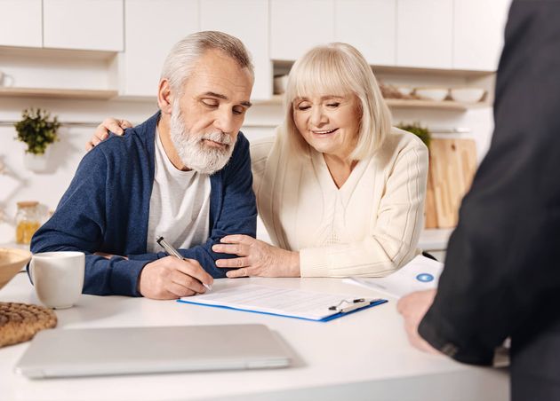 Our Important Day Smiling Involved Delighted Elderly Couple Sitting Home Having Meeting with Broker while Signing Documents