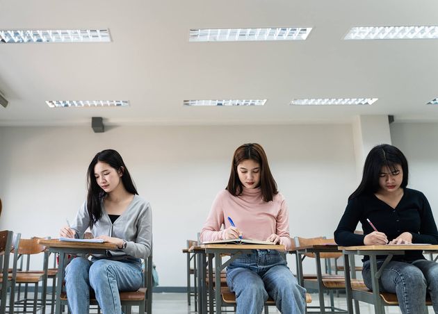 Selective Focus Teen College Students Sitting Lecture Chair Classroom Write Examination Paper Answer Sheet Doing Final Examination Test Female Students Student Uniform