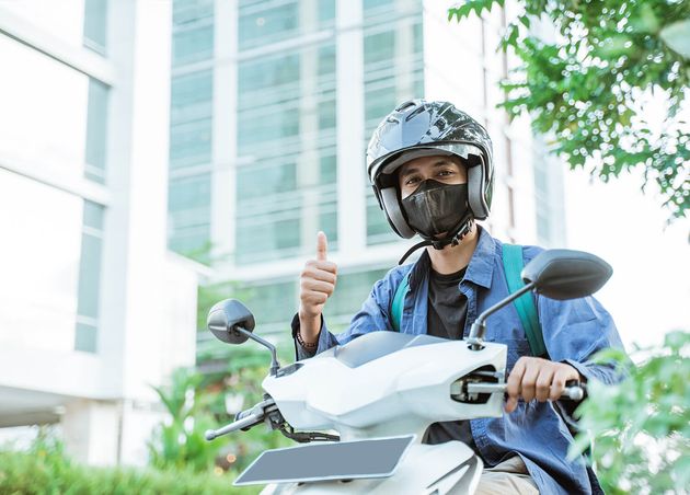 Man Wearing Helmet with Thumbs up Motorcycle City Street Background
