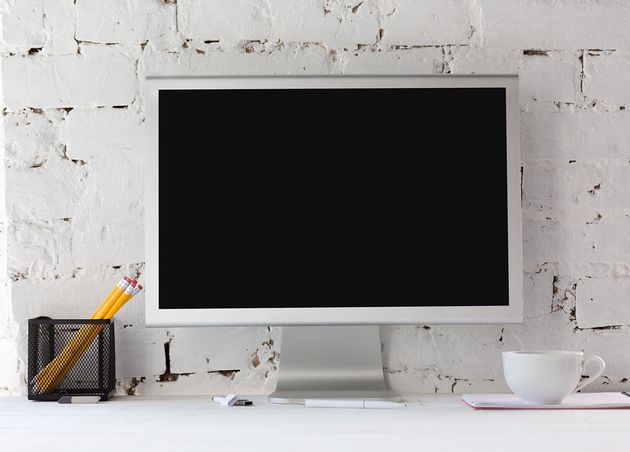 Leerer schwarzer Monitorbildschirm Weiße Ziegelwand mit Bleistiften Notizen Tasse Kaffee Kopierraum