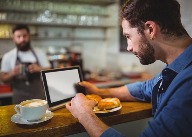 Man Using Digital Tablet while Having Croissant Cafa C