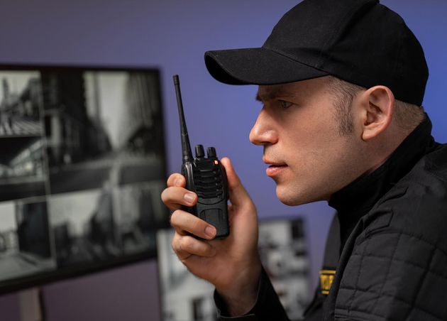 Portrait Male Security Guard with Radio Station Camera Screens