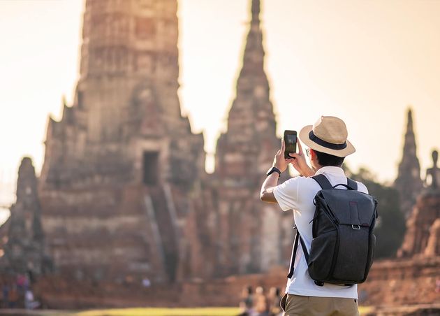 Happy Tourist Man with Backpack Taking Photo by Mobile Smartphone during Visiting Wat Chaiwatthanaram Temple Ayutthaya Historical Park Summer Solo Asia Thailand Travel Concept