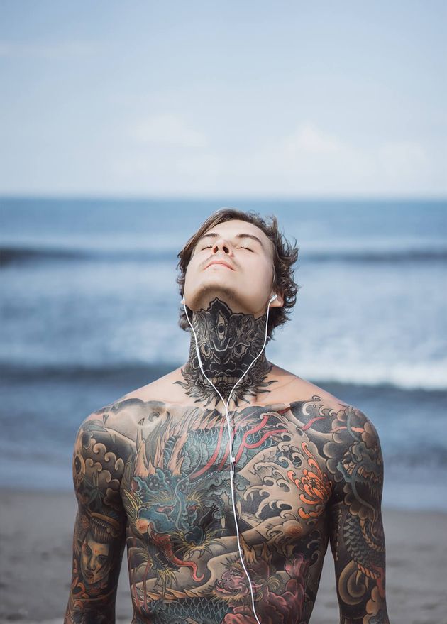 Tattooed Man with Headphones against Blue Sky Ocean