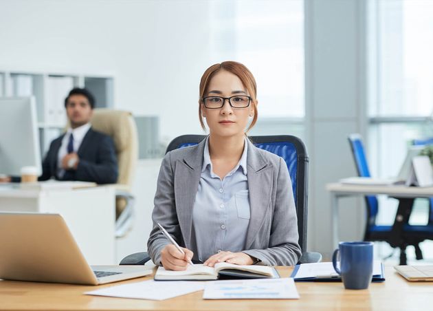 Young Asian Woman Glasses Sitting Desk Office Writing Planner Looking Camera