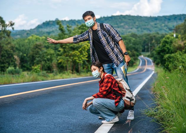 Female Tourists Sit Male Tourists Pretend Hitchhiker Both Wearing Mask Side Road