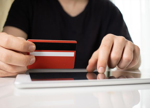Person Holding Red Credit Card Tablet White Surface